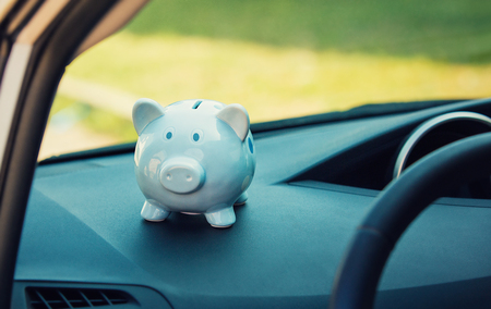 Piggy money box inside a car transportation. Saving money for vehicle purchase. Successful financial planning and banking concept. Economic investment for future. Dealership offering credits.の写真素材