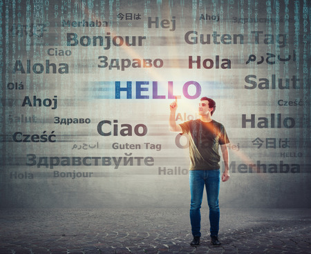 Student guy pointing index finger up choosing word hello with different translations. Multilingual teacher learning and speaking many languages. International communication concept.の写真素材