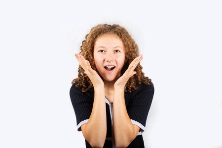Young girl positively surprised with hands on her cheek. Beautiful young woman holding her mouth...