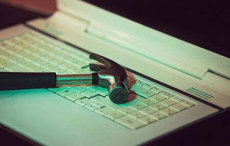 Close up of a hammer on an old laptop keyboard. Computer repair, customer technical support service....