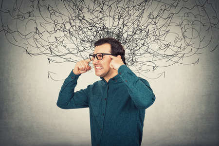 Annoyed irritated businessman, frowning and screaming due noise in head as mess arrows. Fatigue male...