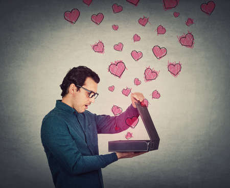 Side view businessman looking inside a briefcase, surprised facial expression, isolated on white background. Shocked and astonished business worker opens a box type portfolio with important securitiesの写真素材