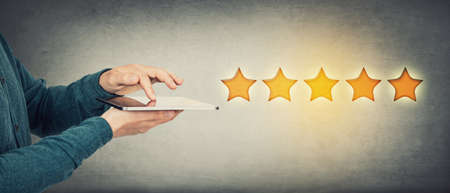 Close up person hands using a PC tablet to check out the rating feedback, evaluating an experience...