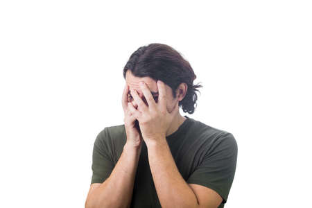 Portrait of disappointed young man, long curly hair style, covers face with his hands, looking down...