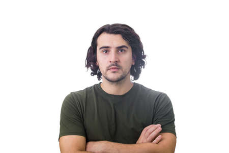 Portrait of serious brunette young man, long curly hair style, keeps arms folded looking confident...