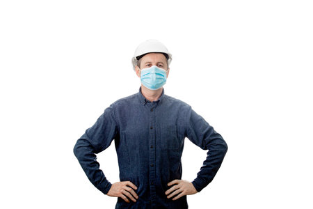 Serious confident middle aged architect wearing protective helmet and face mask protection against the Covid-19 or coronavirus looking to camera isolated over white background ..の写真素材