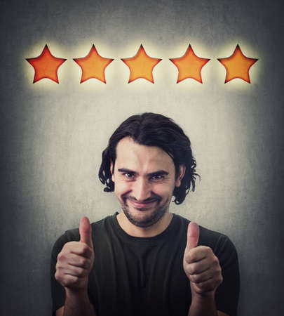 Contented young man, shows both thumbs up gesture, slick smiling to camera. Attractive casual guy,...