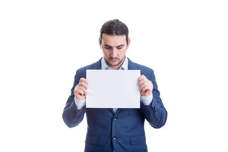 Thoughtful businessman holding a blank paper sheet with copy space, looking down isolated on white backgroundの写真素材