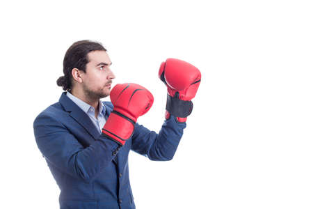 Businessman with red boxing gloves stands in fighting position. Side view portrait of determined business person prepared for battle isolated on white background. Employee self defense conceptの写真素材