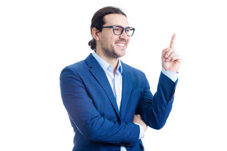 Confident businessman pointing up forefinger smiling isolated on white background. Contented business person, wearing eyeglasses, determined shows index finger upwardsの写真素材