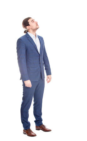 Full length portrait of reflective businessman looking up curious isolated on white backgroundの写真素材