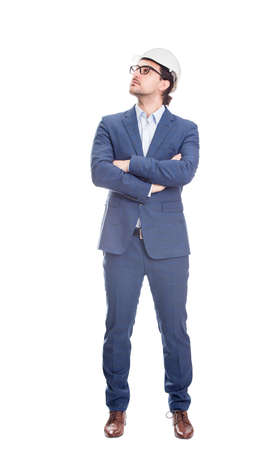 Full length confident engineer, keeps arms crossed wearing protective helmet looks determined aside isolated on white backgroundの写真素材