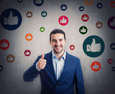 Contented businessman smiling broadly shows thumb up gesture, surrounded by multicolored like...