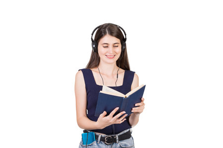 Positive young woman reading a books while listening to music isolated on white backgroundの写真素材