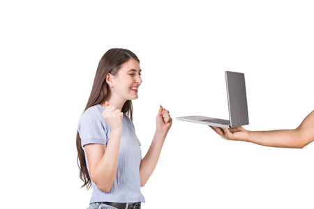 Outstretched person hand holding a laptop showing the screen to a joyful young woman isolated on white background. Girl celebrating success as watching a notebook displayの写真素材
