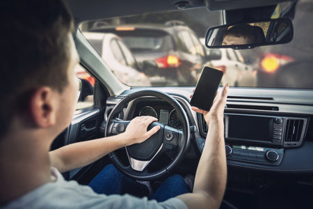 Furious man driver honking the car horn angry on the traffic jam ahead. Aggressive guy unsafe driving while using his phone in front of the steering wheel, violating the rulesの写真素材
