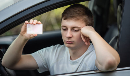 Upset driver showing his driver license out of the car window as for police check control. Driving unsafe violating traffic regulationsの写真素材