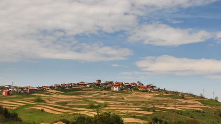 Classic Rhodope mountain landscape. A village on the hill and plowed fields.の写真素材