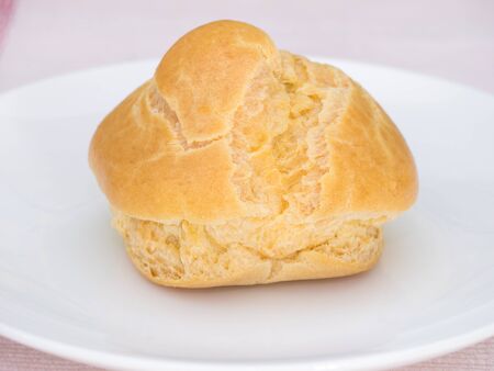 Cream puff on white dish, on pink tablecloth, Homemade style
