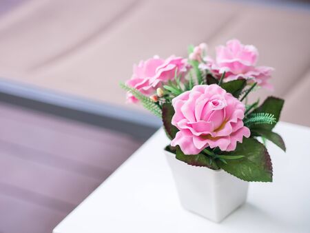 Bouquet Pink roses in the white vase, Artificial or fake flowers decorated on white table, with wooden background.の写真素材