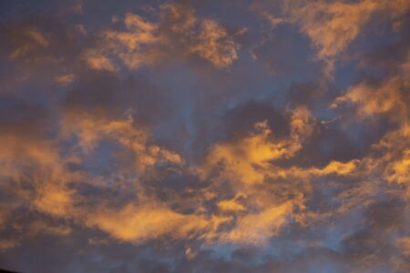 golden, dark and rose clouds in the sky during sunset or sunrise with blue sky