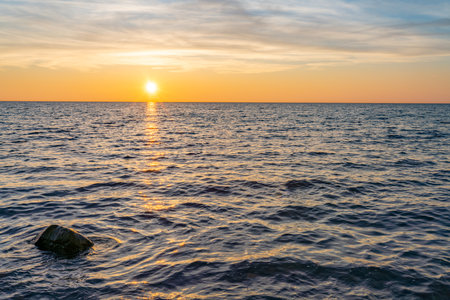 dreamlike, orange, sunset between rocks in the sea of the Baltic Sea near Dranske on the island of RÃ¼gen- Beautiful sunset over the sea with waves and rocks in the foregroundの写真素材