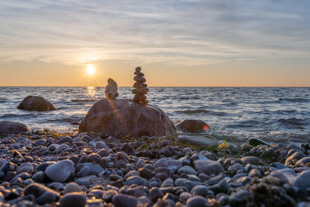Sunset on the beach with a stack of stones in the foreground - Stone pyramids and glass sphere on the dreamy Baltic Sea sand beach on RÃ¼gen for the spectacular sunsetの写真素材