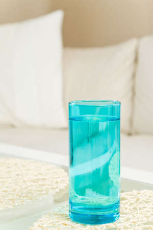 Blue water in a glass on a table in a livingroomの写真素材