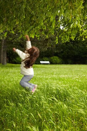Young girl jumping up to reach a willowの写真素材