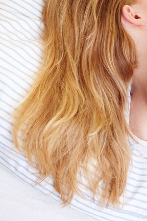 Long blond hairs on the sheets in a bed