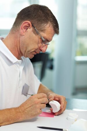 Dental technician working on dentures with a probeの写真素材