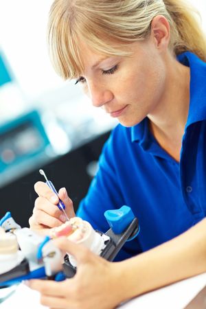 Dental technician working on dentures with an articulator