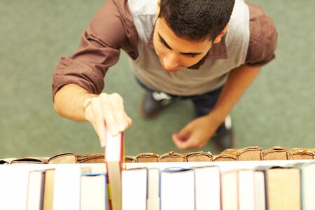 Student taking a book from shelf in library