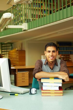 Friendly librarian sitting at desk with books