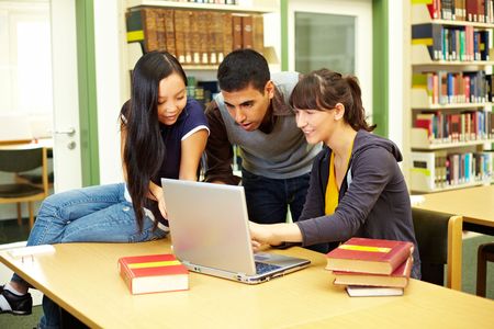Three happy students learning in university library