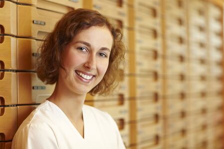 Female pharmacist at medicine cabinet in pharmacyの写真素材