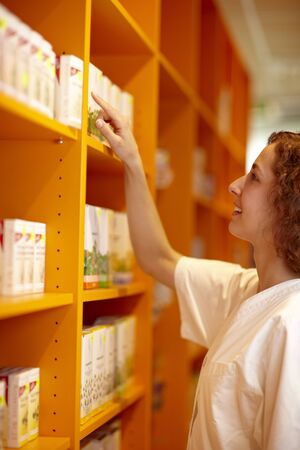 Female pharmacist looking for medicine in shelfの写真素材