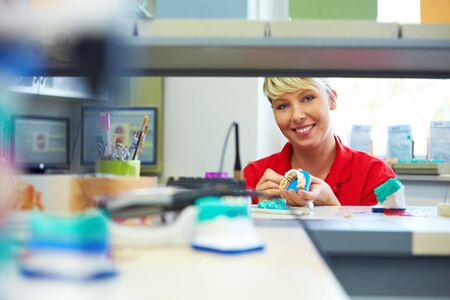 Happy dental technician working on a zircon bridgeの写真素材