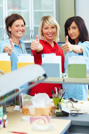 Three dental technicians showing her thumbs upの写真素材