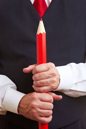 Hands holding a big red oversized pencilの写真素材