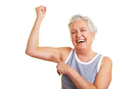 Happy senior woman showing her upper arm musclesの写真素材