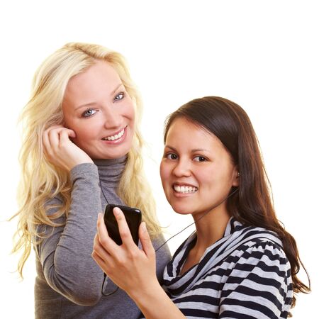 Two happy women listening to music with mobile phone