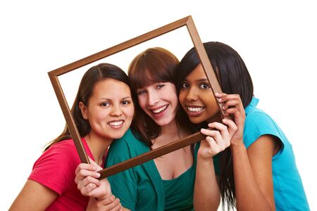 Three young beautiful women looking through an empty frame
