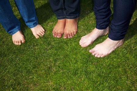 Three women with naked feet standing in grassの写真素材