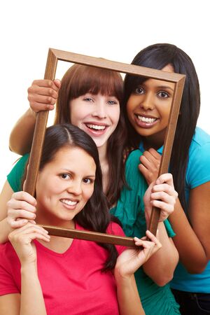 Three young beautiful women looking through an empty frameの写真素材