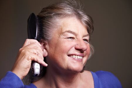 Happy senior woman brushing her gray hair