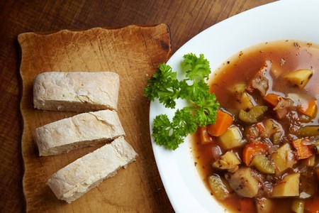 Vegetable soup in a soup plate with ciabatta as side dishの写真素材