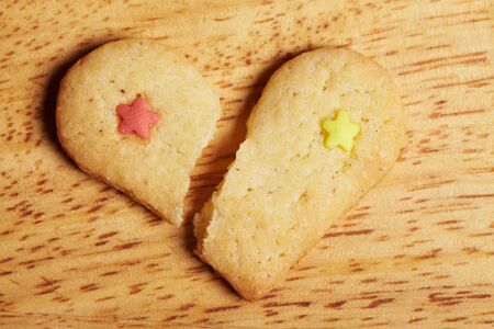 Broken decorated cookie heart on wooden baseの写真素材