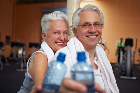 Two happy senior people in a gym drinking waterの写真素材