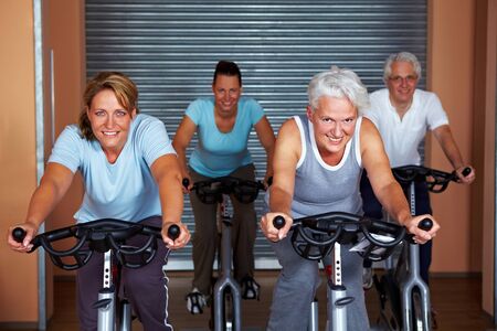 People in a gym sitting on spinning bikesの写真素材